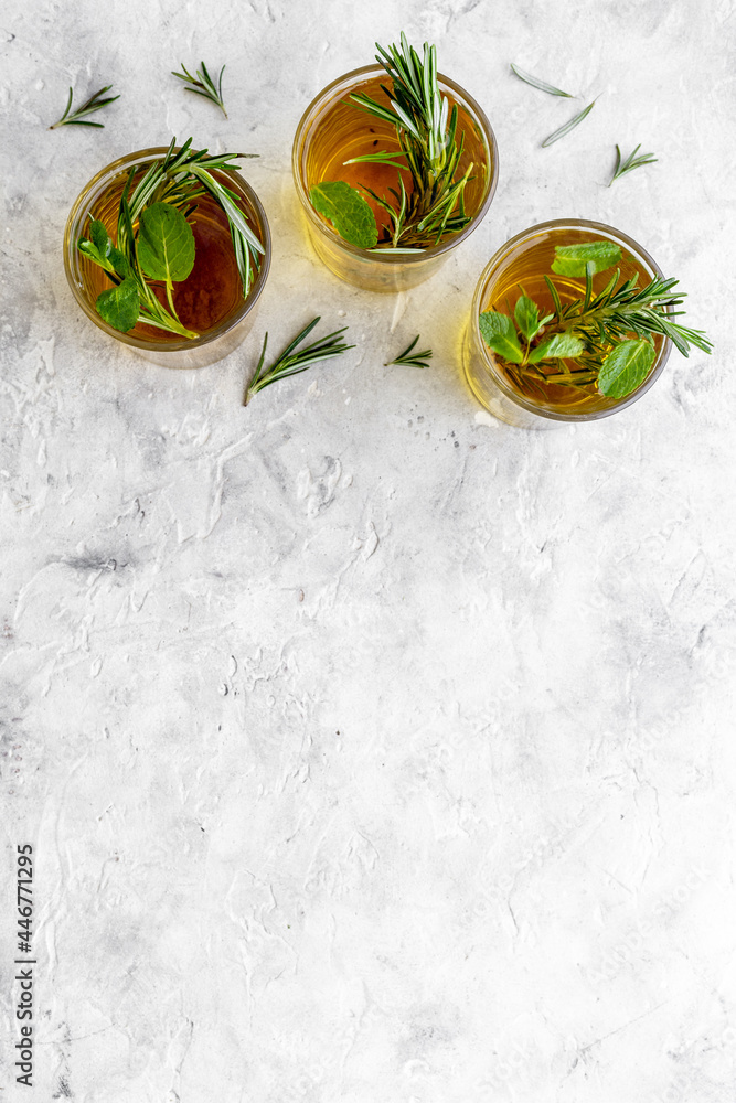 A lot of glasses of lemonade with cold tea and rosemary