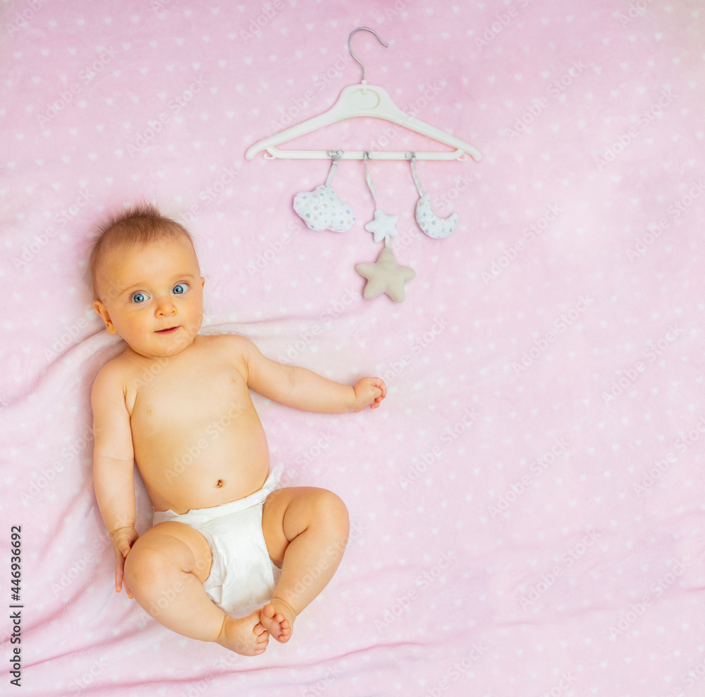 Cute baby girl and mobile toys on pink blanket