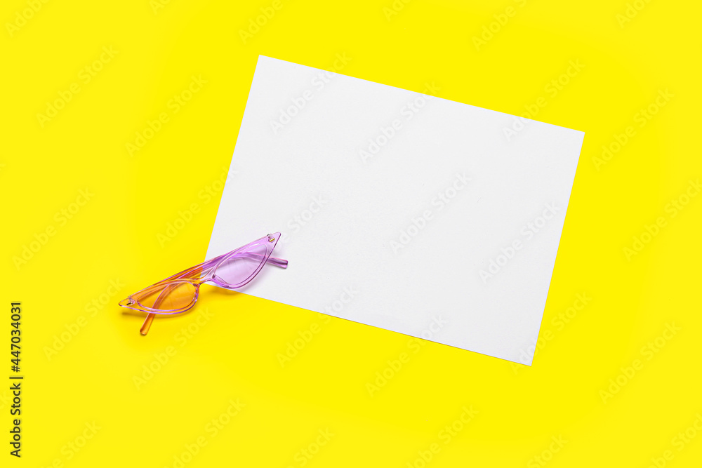 Stylish sunglasses and blank sheet of paper on color background