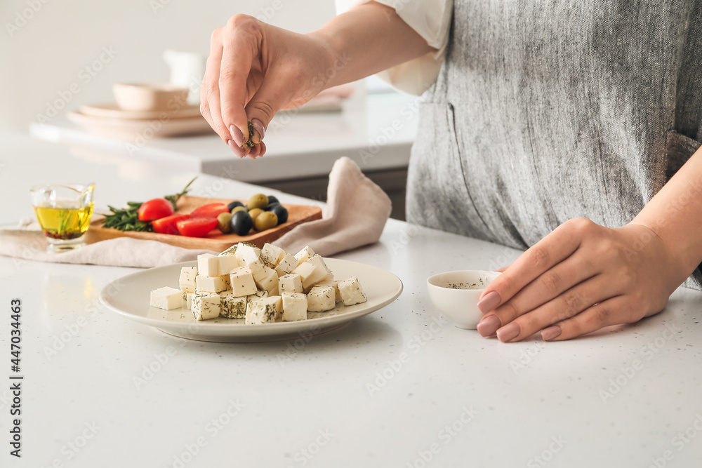 一位女士在餐桌上为美味的羊乳酪添加香料