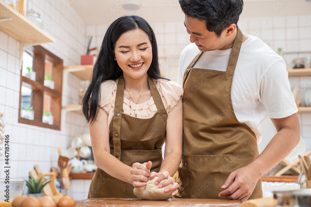 亚洲新婚夫妇待在家里，在厨房里共度时光。