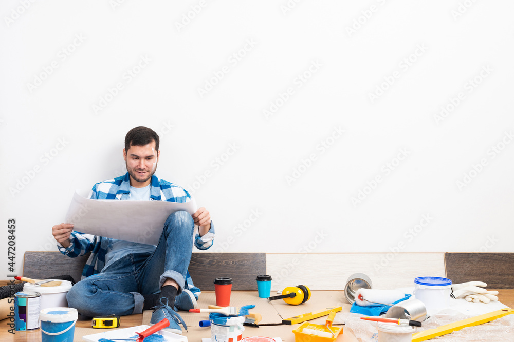 Guy looking at paper blueprint while sitting