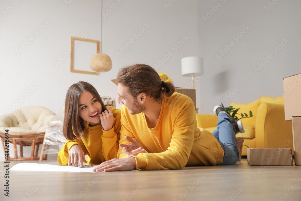 Young couple with house plan in their new house on moving day