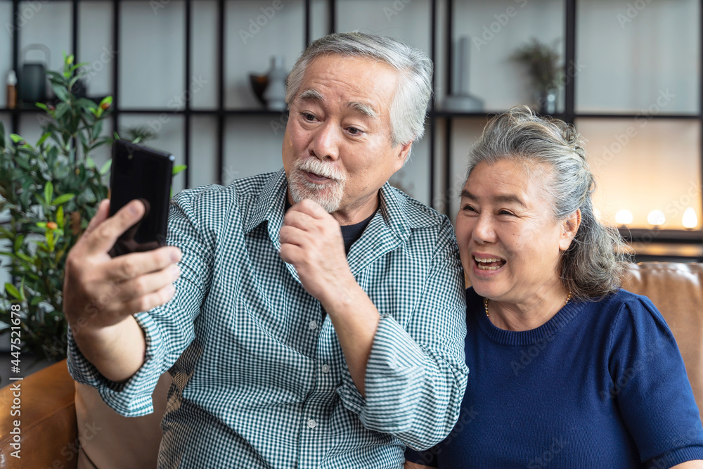 happiness asian old senior retired couple enjoy videocall to family together on sofa in living room 