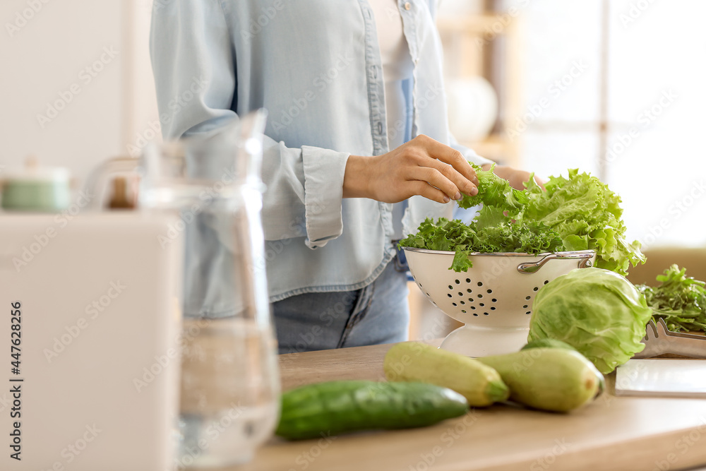 Young woman cooking fresh salad in kitchen