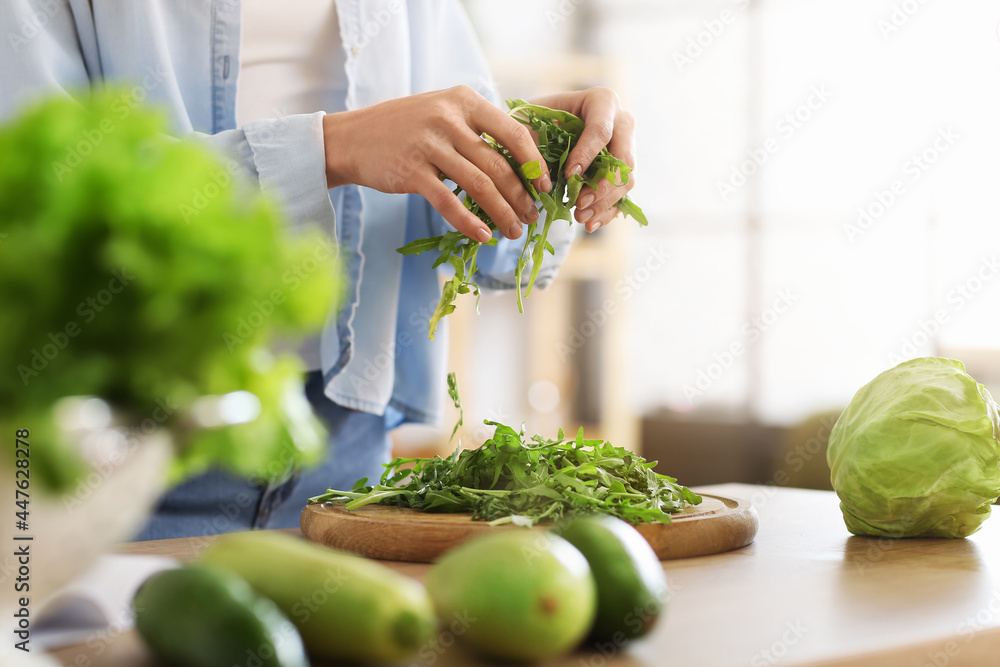 Young woman cooking fresh salad in kitchen