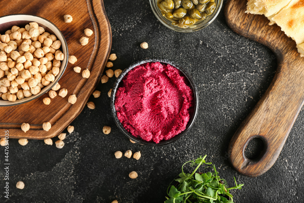 Composition with tasty beet hummus, capers, fresh sprouts and chickpeas on dark background