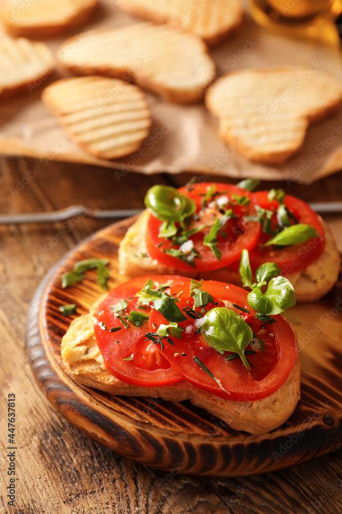 Tasty bruschettas with tomato and hummus on wooden background, closeup