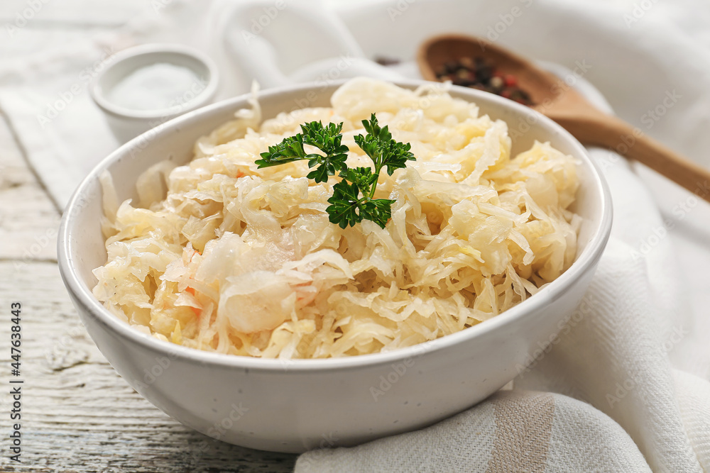 Bowl with tasty sauerkraut on light wooden background