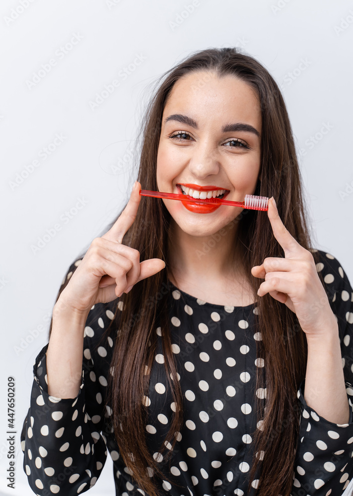 红唇可爱女孩的垂直视图在刷牙时将牙刷保持在健康的白色牙齿之间