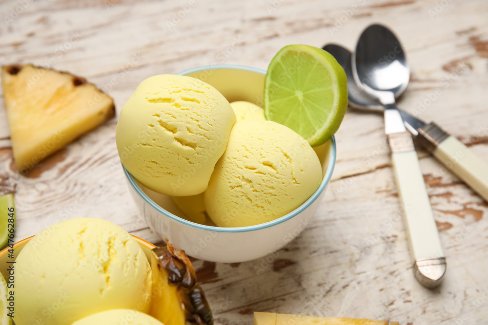 Bowls with tasty pineapple ice cream and lime on light wooden background, closeup