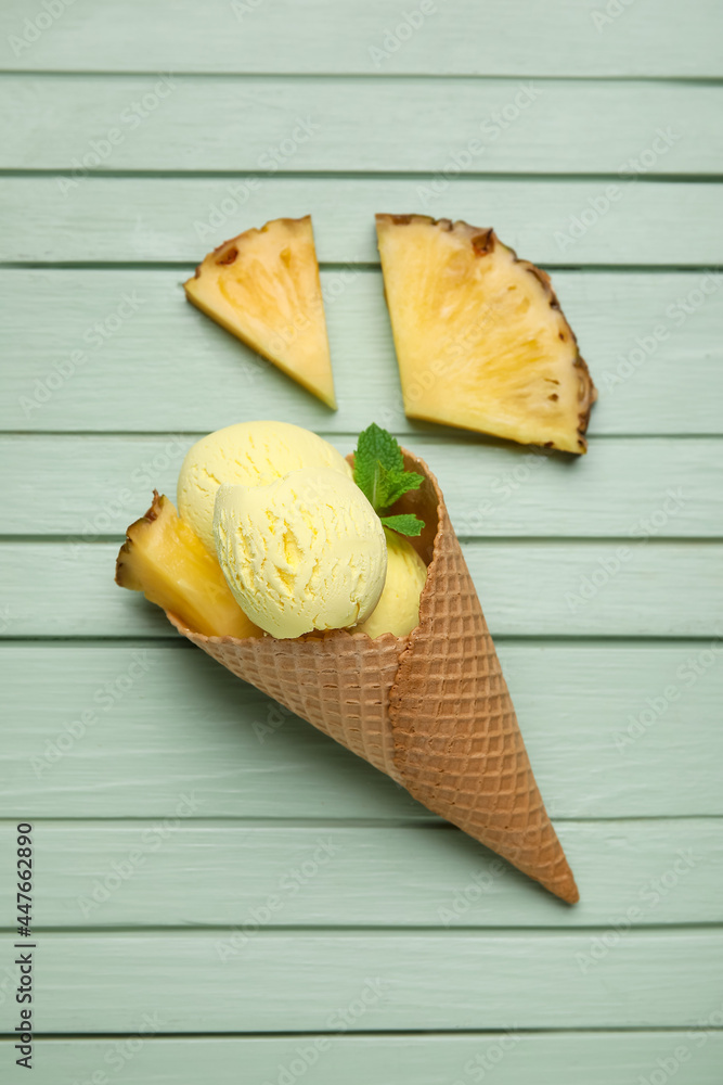 Wafer cone with tasty pineapple ice cream on color wooden background