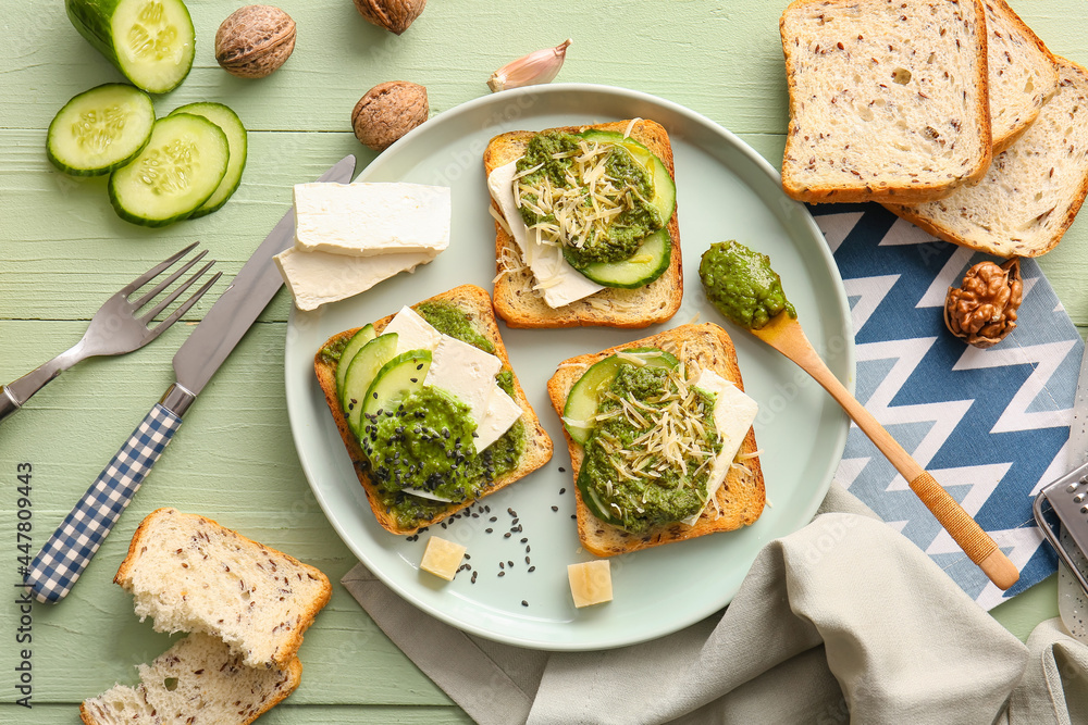 Tasty toasts with pesto sauce on color wooden background