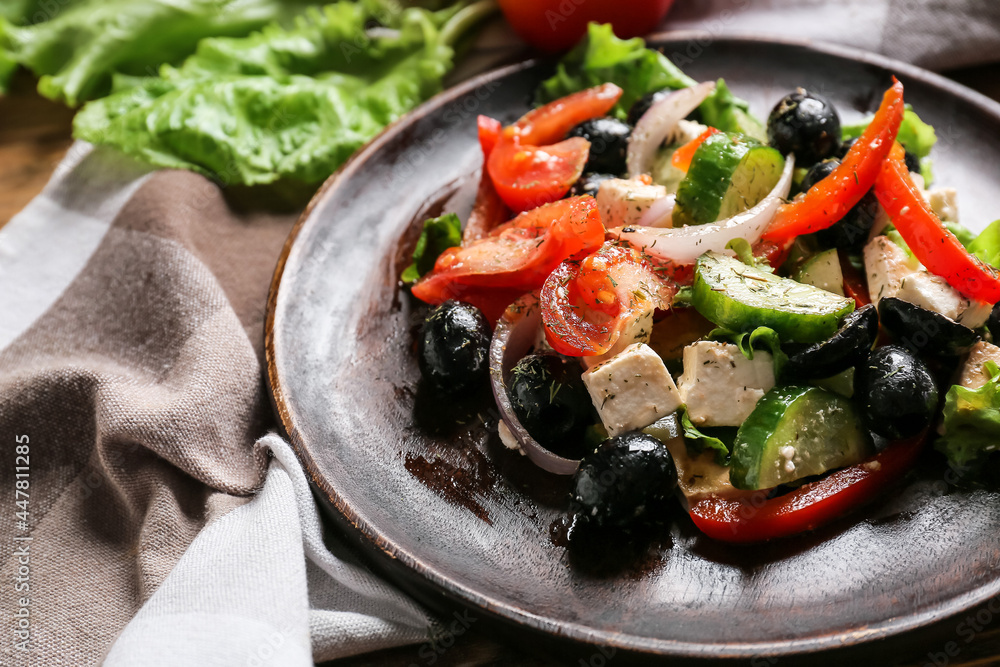 Plate with tasty Greek salad on wooden background, closeup