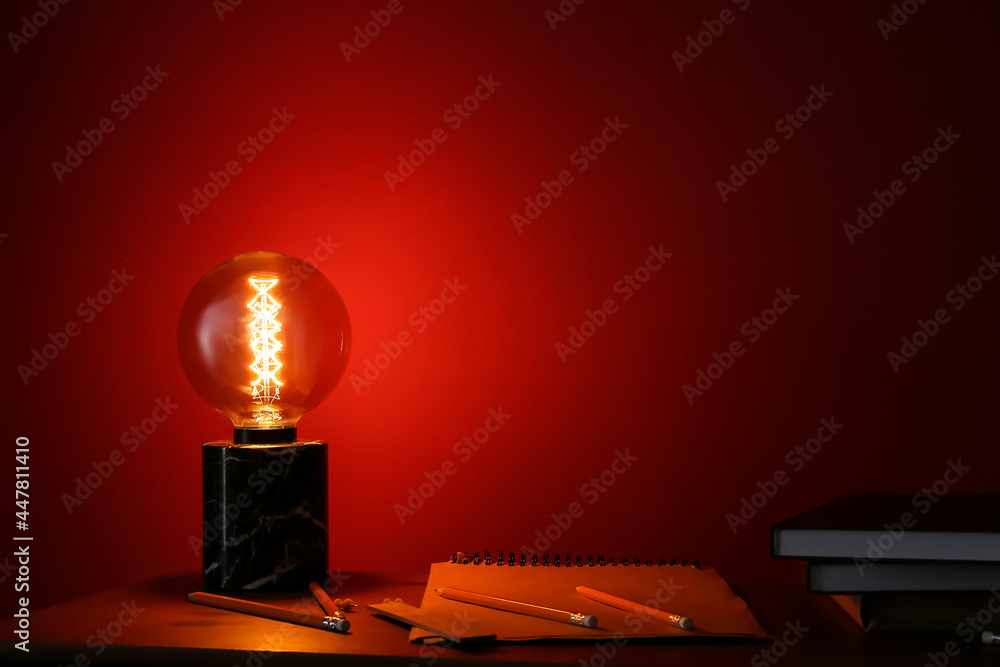 Glowing lamp with books on table in dark room