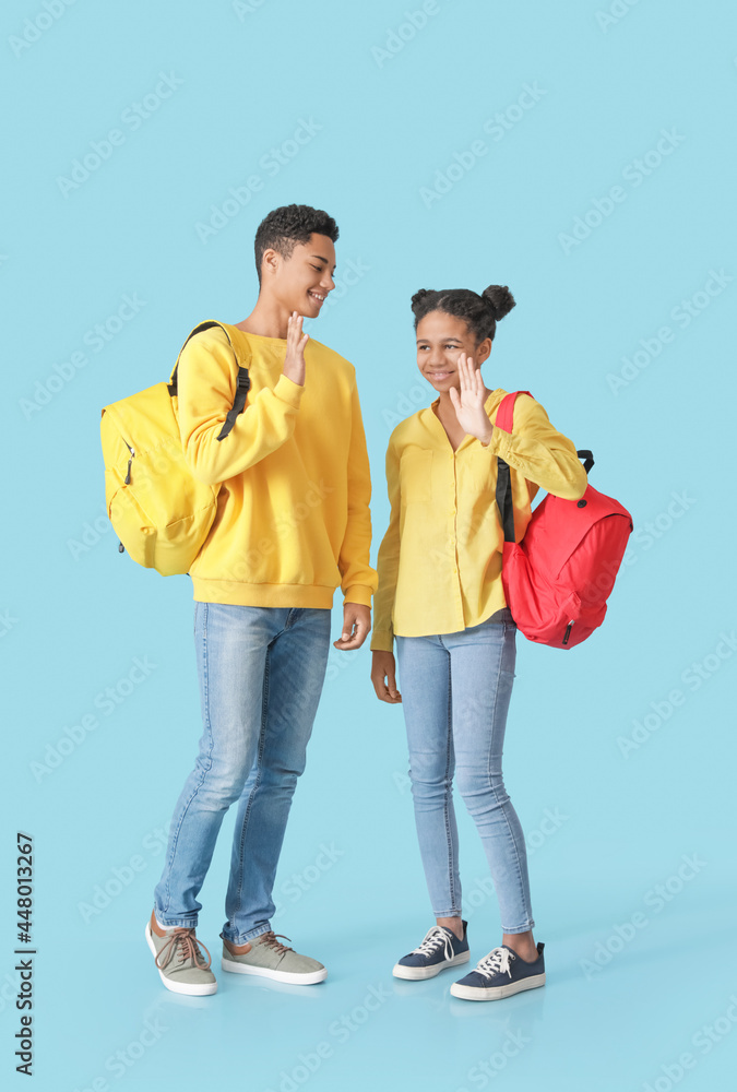 African-American brother and sister giving each other high-five on color background