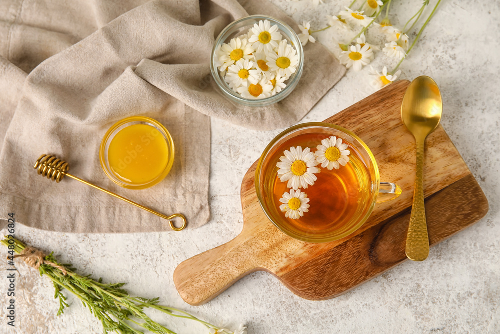 以一杯洋甘菊茶、花朵和蜂蜜为浅色背景的成分