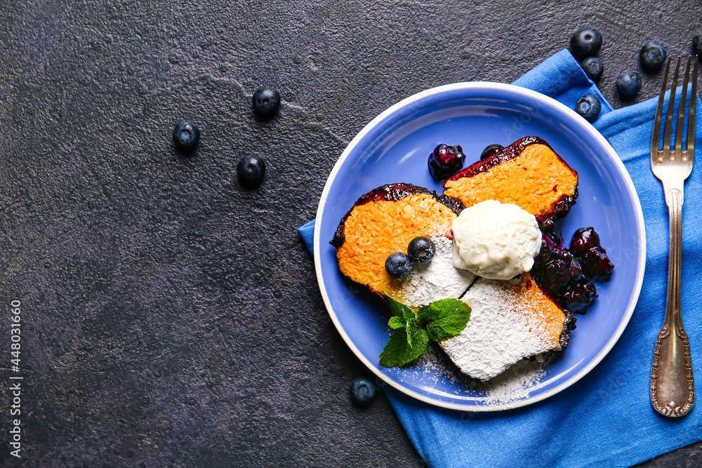 Plate with pieces of blueberry cobbler and ice cream on dark background