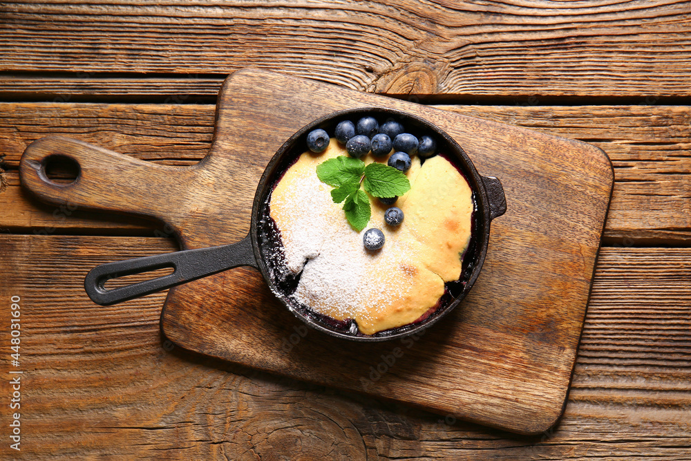 Frying pan with blueberry cobbler on wooden background