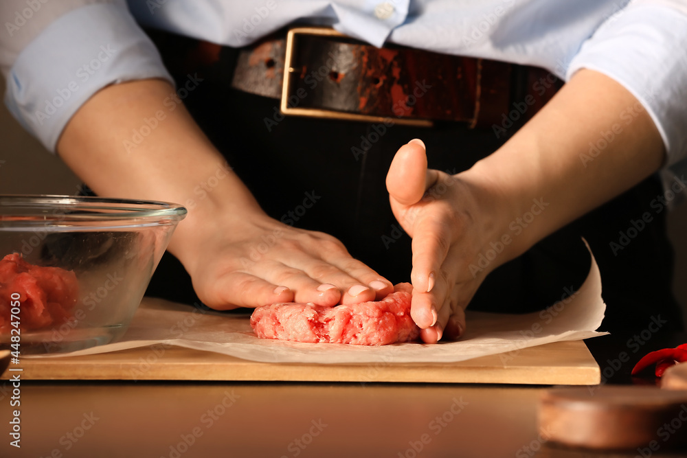 Woman preparing tasty cutlets made of fresh forcemeat on dark background, closeup