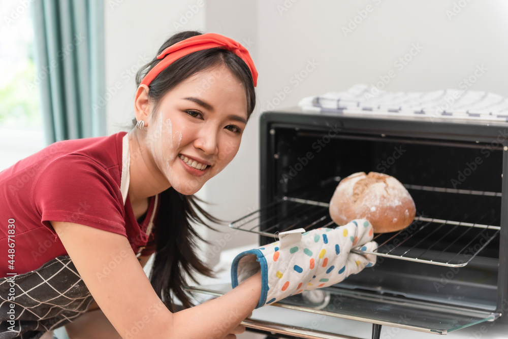 面包房里，一位面包师女士自豪地看着镜头，在船上展示面包。