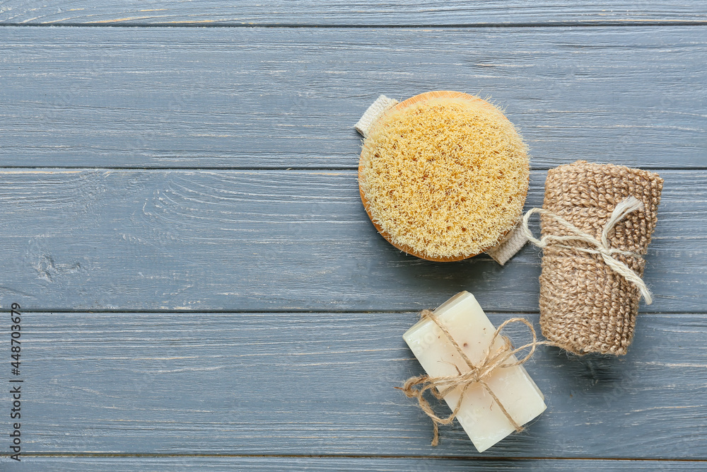 Massage brush and bath supplies on dark wooden background