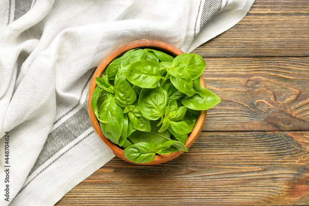 Bowl with fresh basil leaves on wooden background