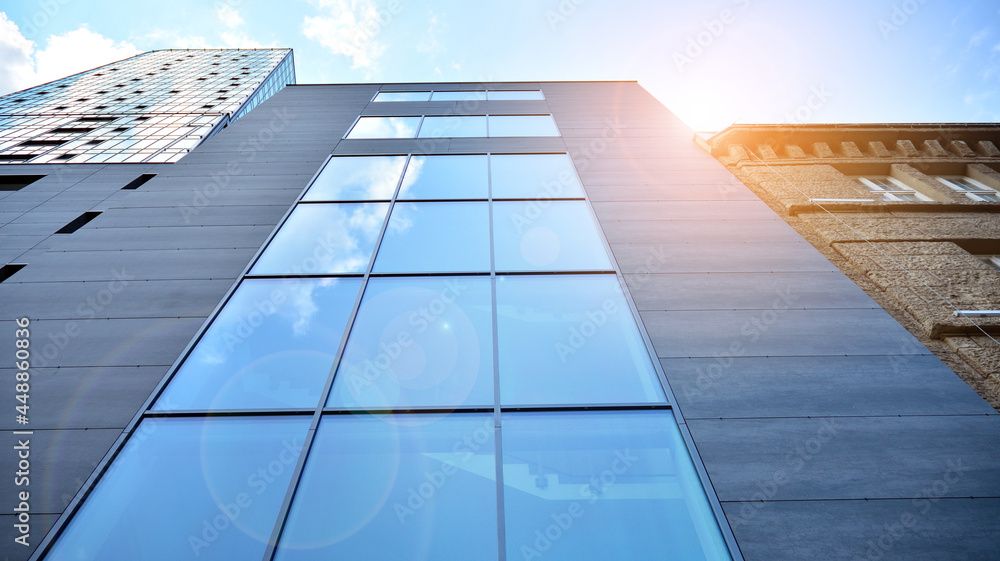 Glass and steel. Mirrored facade of modern office building with sunbeams glare reflection