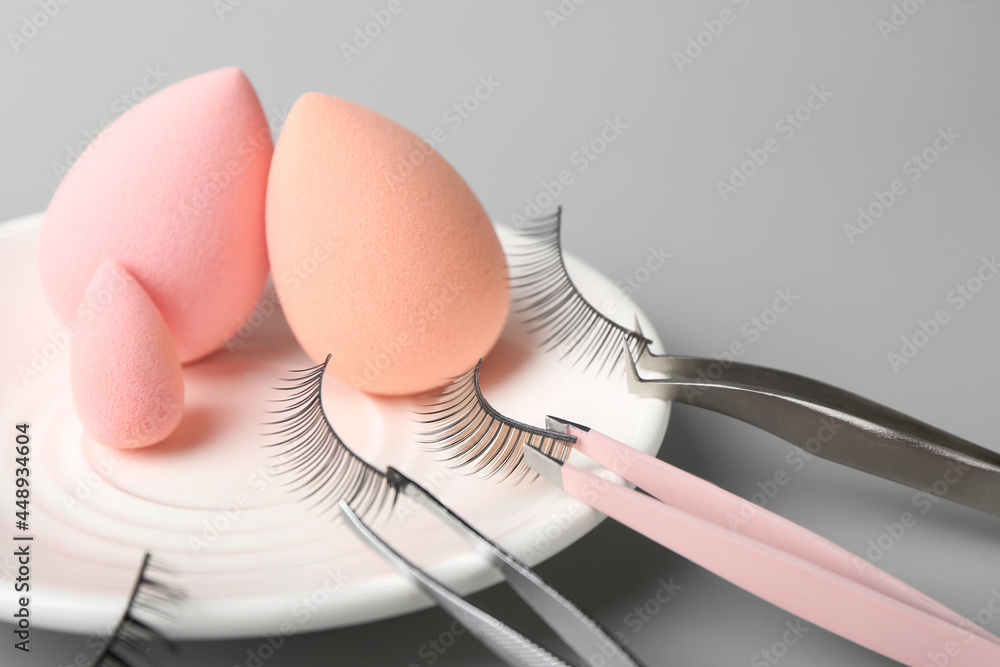 Composition with false eyelashes and tools on grey background, closeup