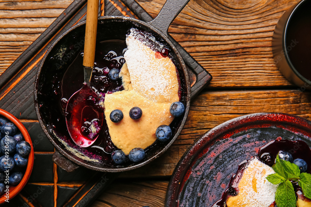 Frying pan with blueberry cobbler on wooden background