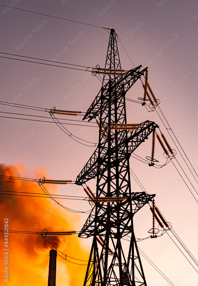 Electrical industrial distribution line. Silhouette of electric construction in orange sunlight.