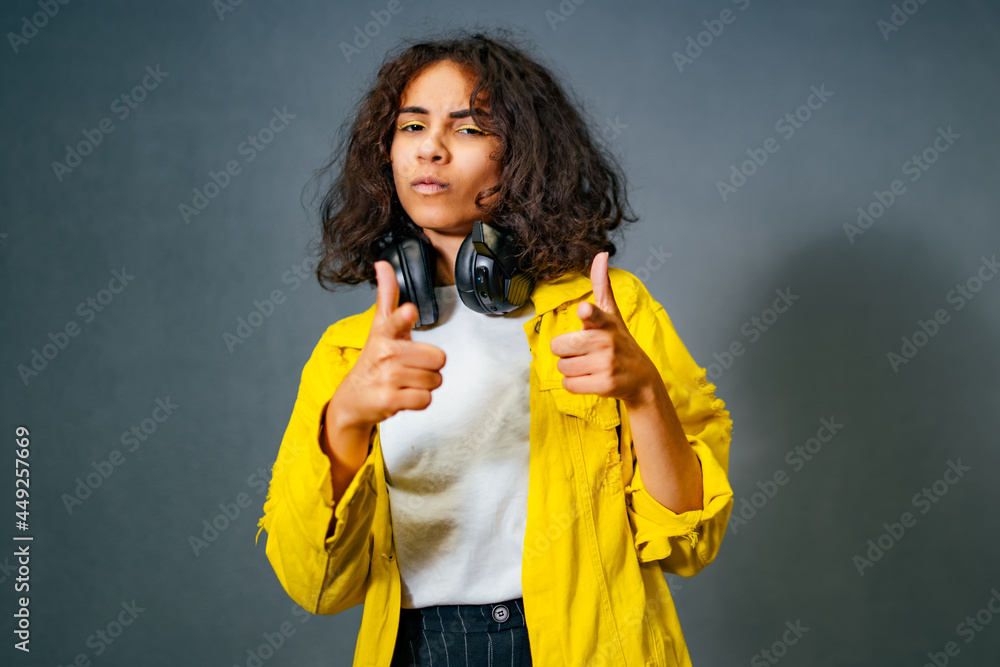 戴着耳机微笑着对着镜头做手势的快乐情绪少女的肖像。戴着