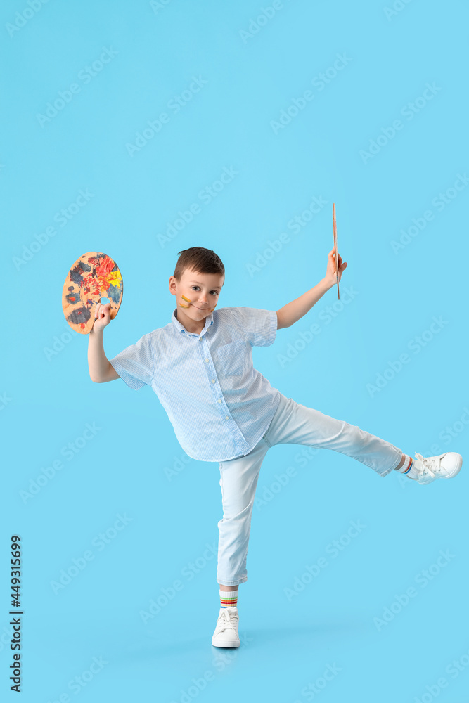 Cute little boy with paint palette and brush on color background