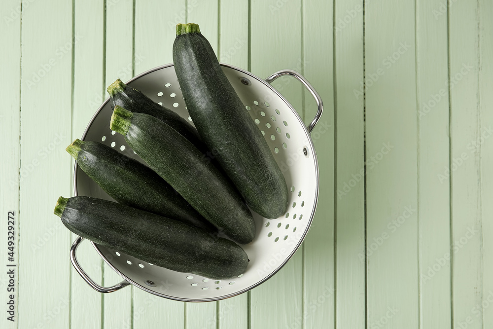 Colander with fresh zucchini squares on color wood background（在彩色木质背景上用新鲜西葫芦南瓜烹制的香菜）