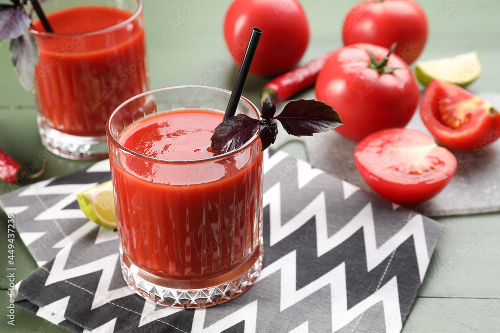 Glasses of tasty tomato juice on color wooden background