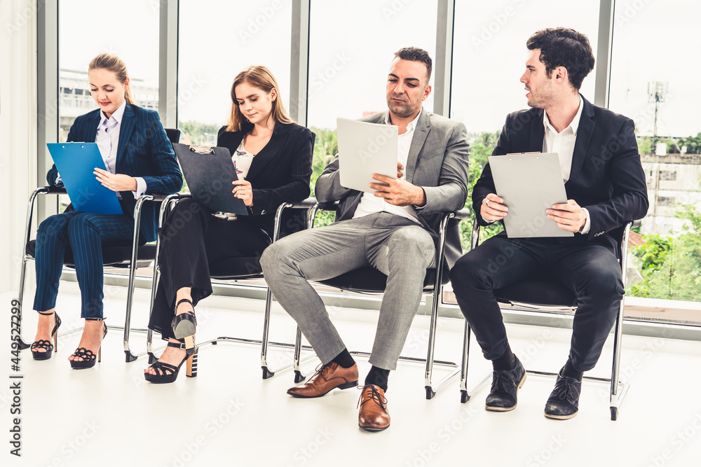 Businesswomen and businessmen holding resume CV folder while waiting on chairs in office for job int