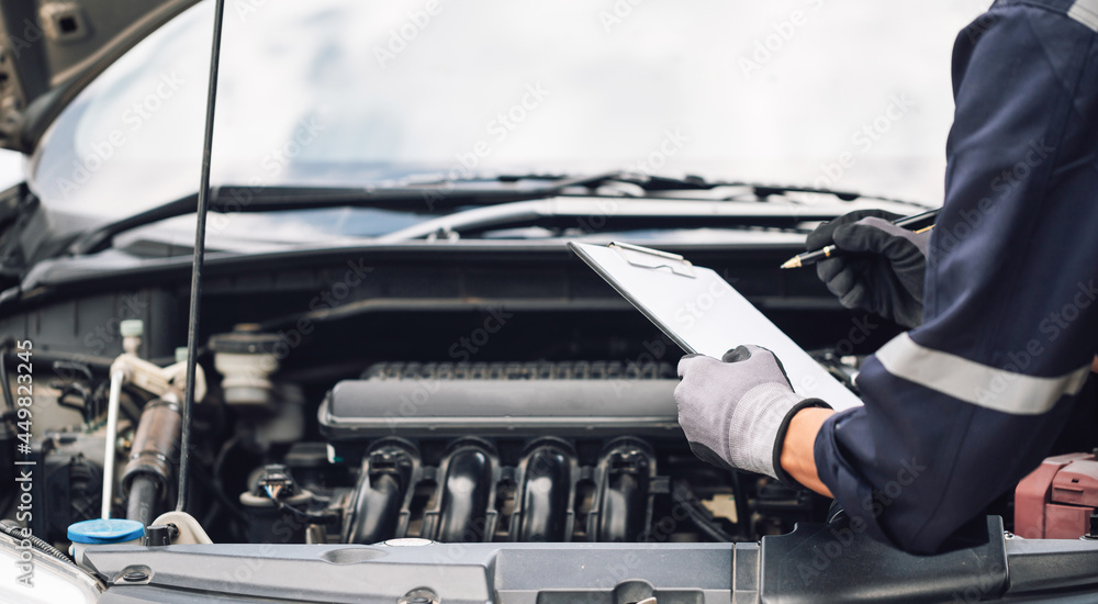 Car service, repair, maintenance concept,auto mechanic man or Smith writing to the clipboard at work