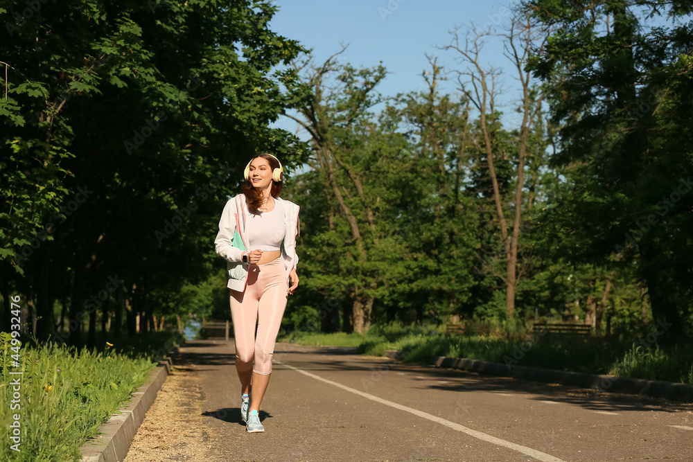 运动型年轻女子在户外跑步时听音乐