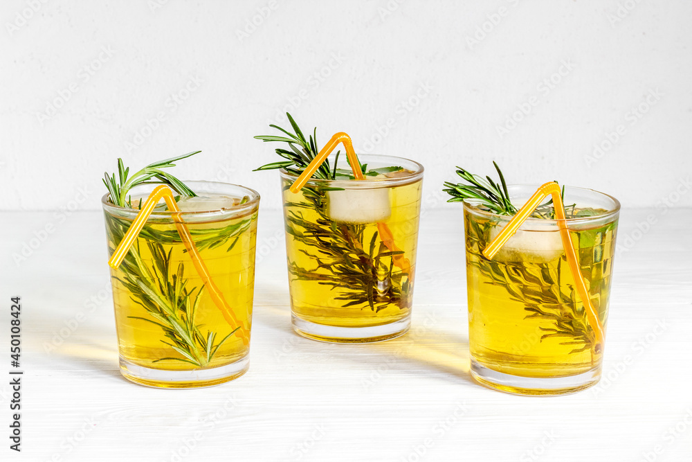 A lot of glasses of lemonade with cold tea and rosemary