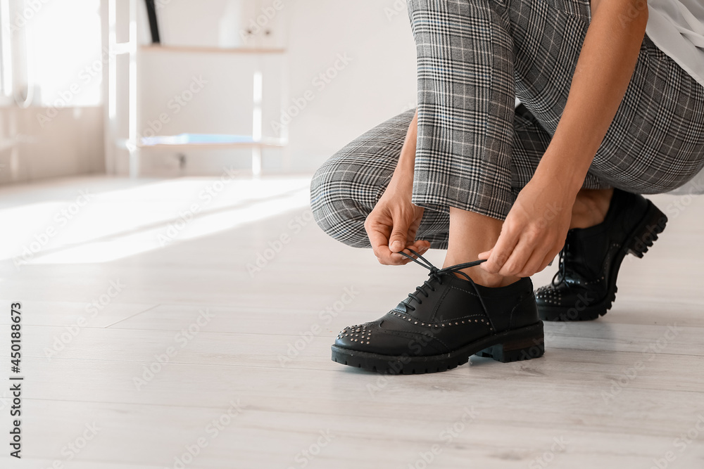 Young woman tying shoe laces at home