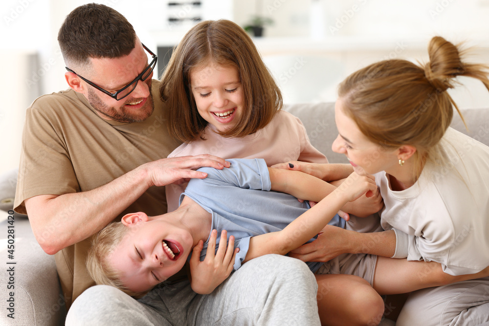 Happy beautiful family having fun and playing while relaxing on sofa in living room