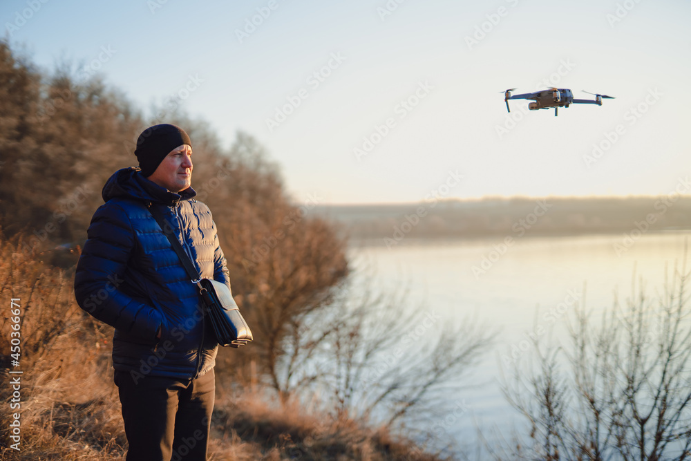 Operator looking at his quadrocopter. Man photographer with dron. Aeromodelling, hobby, leisure conc