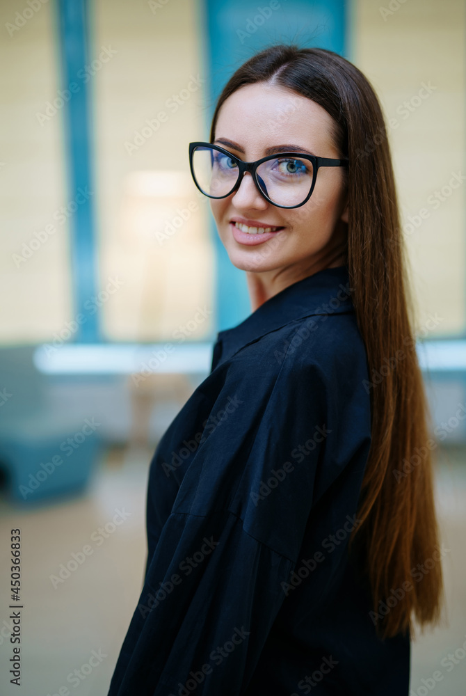 Young attractive girl posing in a black shirt in a light interior. Portrait of elegant woman with gl