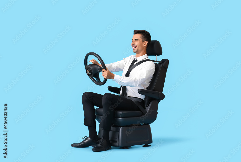 Businessman in car seat and with steering wheel on color background