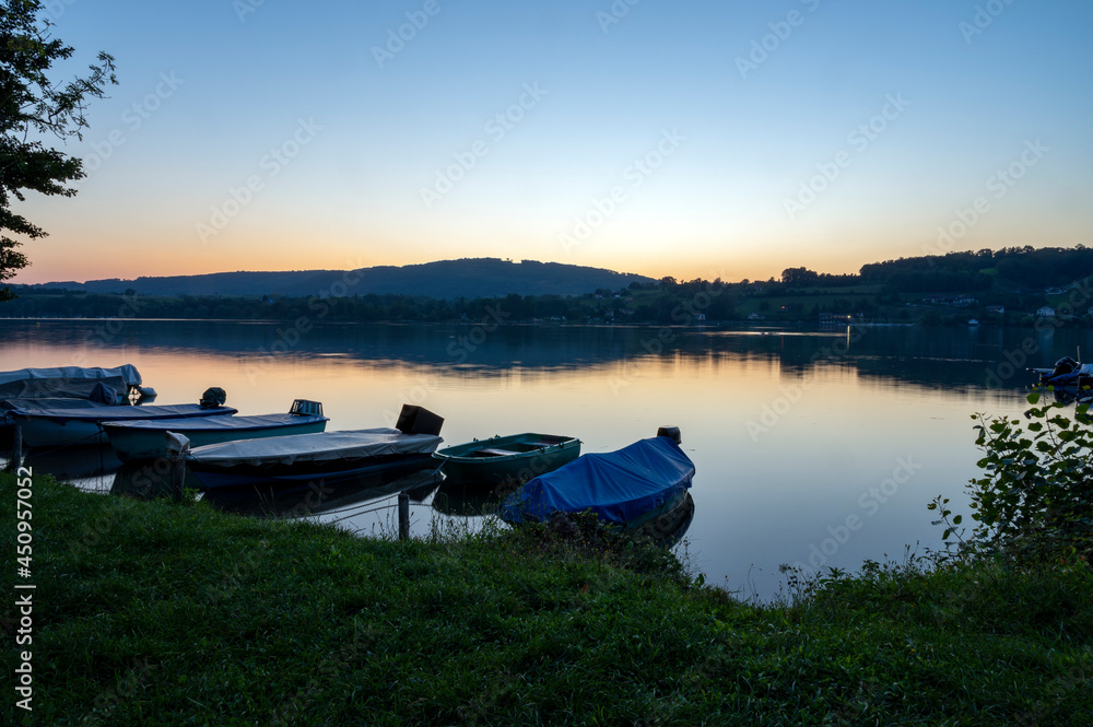 Coucher de soleil sur le lac de Paladru en france en Isère en été avec des bateaux en premier plan