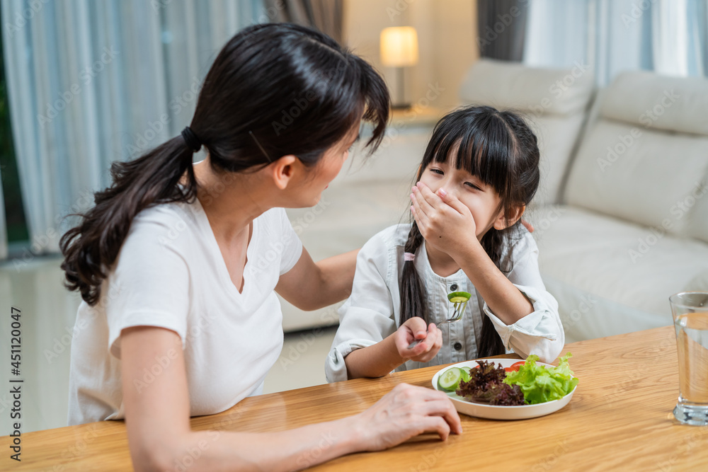 亚洲母亲教导和激励年轻女孩吃绿色蔬菜