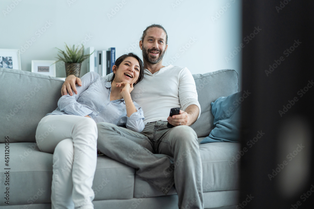 Caucasian loving couple watch movie together in living room at home. 