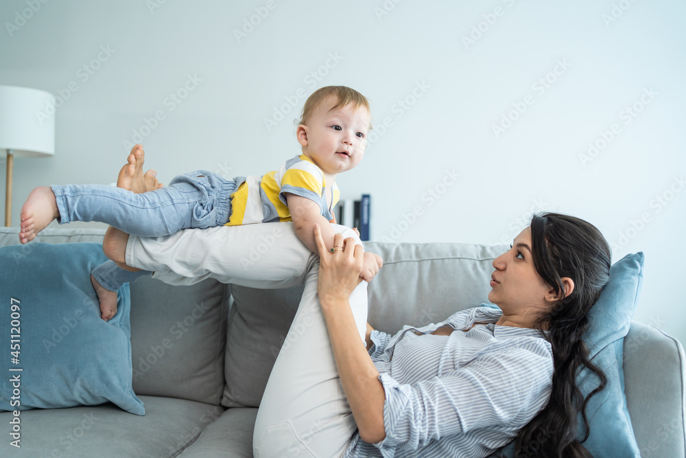 爱高加索的妈妈在客厅的沙发上和男婴玩耍。