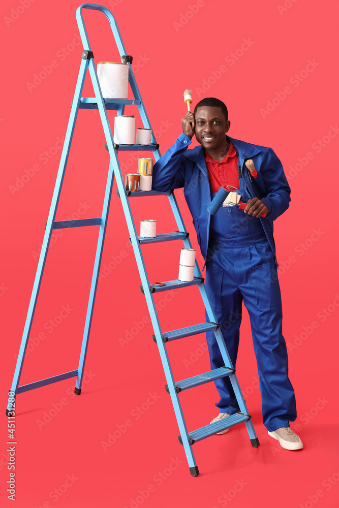 African-American decorator with tools and ladder on color background