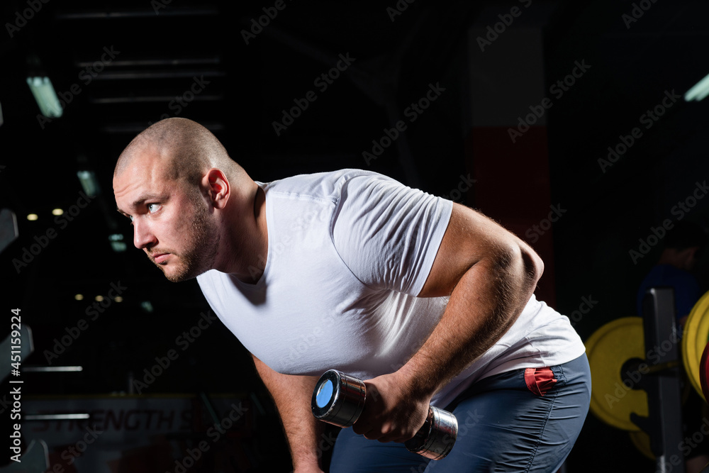 Male bodybuilder engaged with dumbbells in the gym